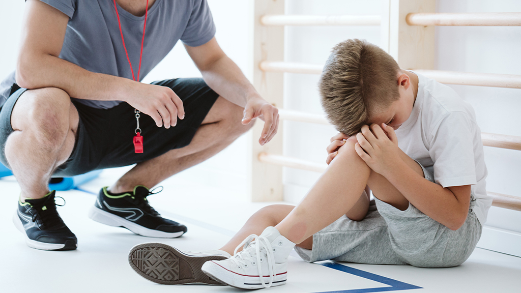 Young boy injured on the edge of a sports field.