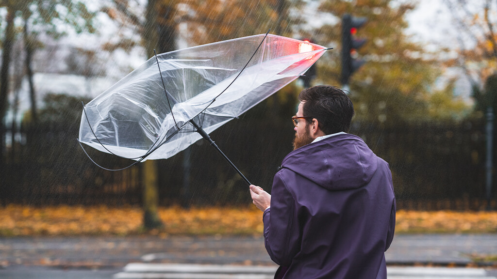 Homme dans la tempête avec un parapluie pris dans le vent