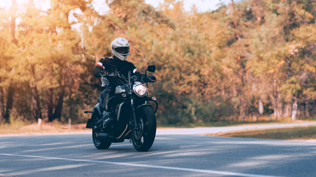 Motard sur sa moto de route noire pendant une balade en forêt