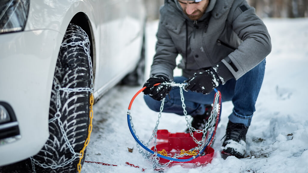 Man putting chains on his car tyres in winter