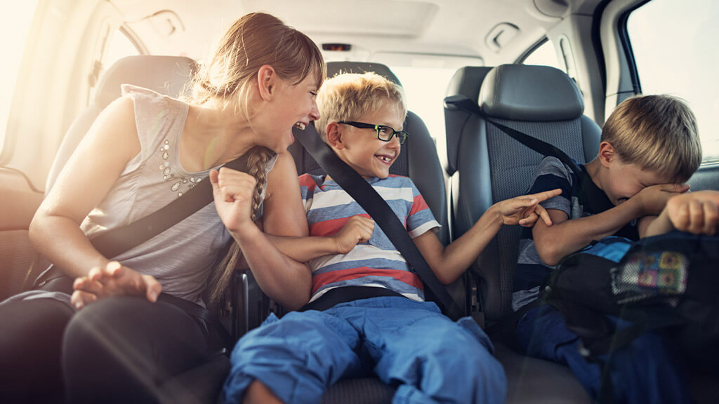 trois enfants qui s'amusent à l'arrière d'une voiture